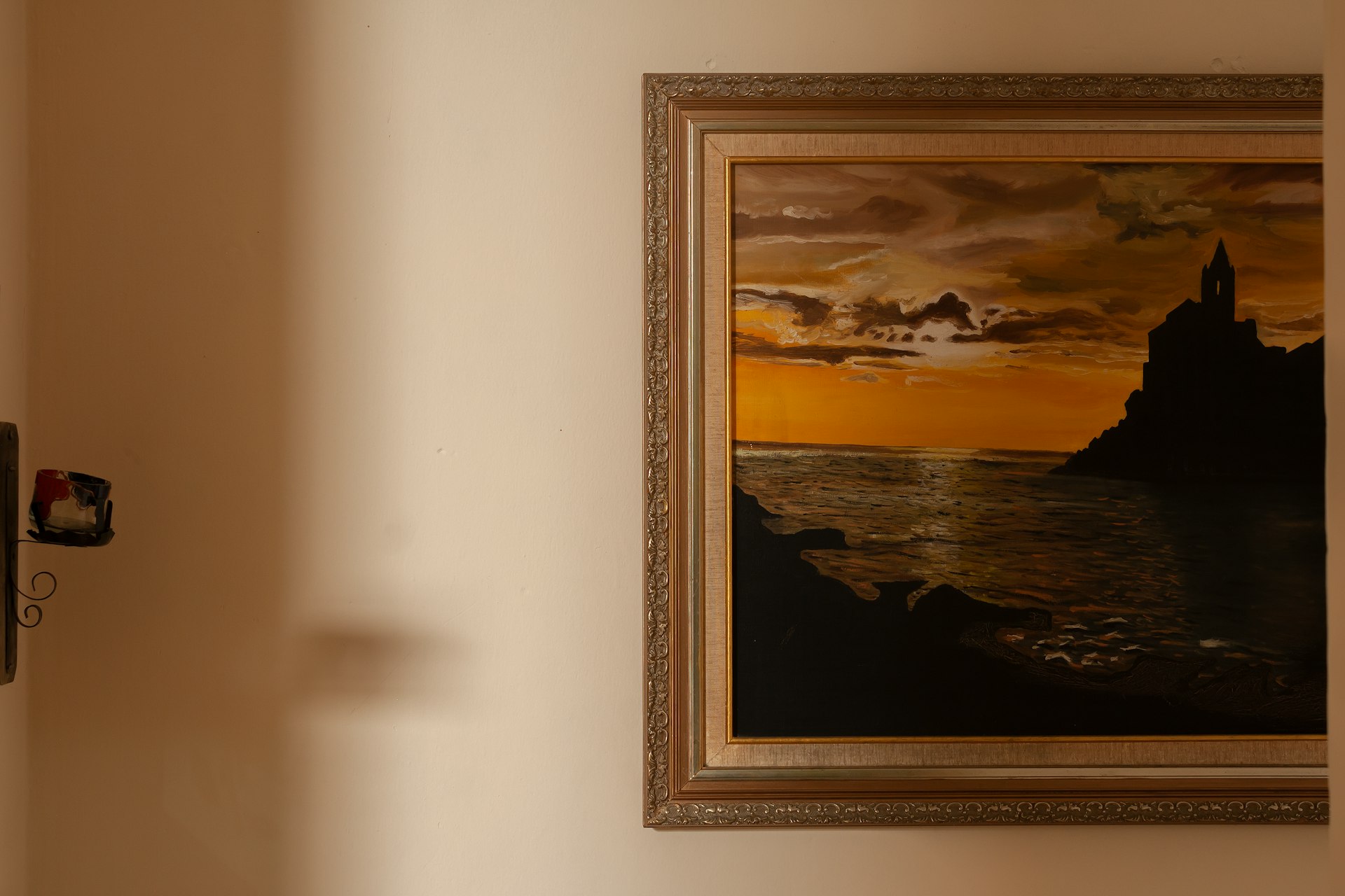 A framed painting depicts a sunset over water.